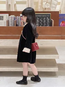 Détail du mini sac boîte matelassé rouge avec chaîne dorée et robe en velours noir
