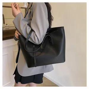 Detailed shoulder view of a black large tote bag with pebbled leather texture on a model
