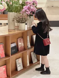 Détail d'un mini sac bandoulière matelassé rouge avec chaîne dorée et boucle fleur