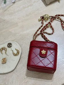 Détail d'un mini sac matelassé rouge avec fermoir camélia doré et bandoulière chaîne