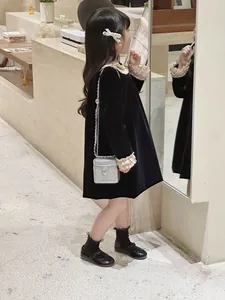 Vue détaillée d'une robe en velours noir pour enfant avec volants et petit sac argenté