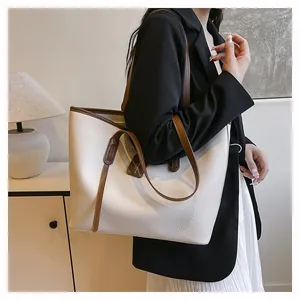 Detail of minimalist cream tote bag with brown straps and textured leather finish