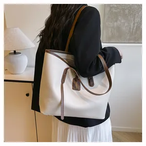 Detail view of large white tote bag in lychee texture leather with brown straps and tag