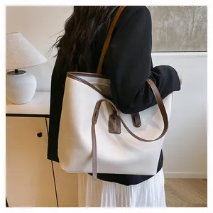 Close-up of white pebble-textured tote bag with contrast brown straps and leather tag detail
