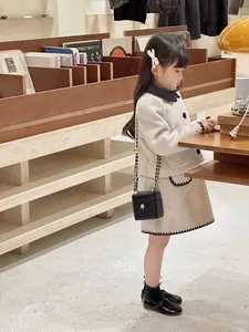 Détail d'un tailleur en tweed pour enfant avec sac matelassé à chaîne en beige et noir