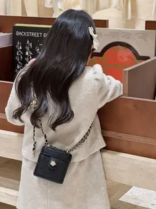 Gros plan du mini sac à chaîne matelassé noir avec fermoir camélia sur un enfant