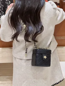 Détail d'un mini sac matelassé avec une fleur de camélia dorée et bandoulière chaîne