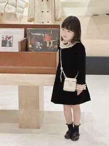 Détail d'une robe en velours pour fille avec col en dentelle et sac à chaîne matelassé