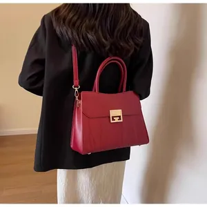 Detail of red wedding handbag featuring gold buckle and textured panel on model