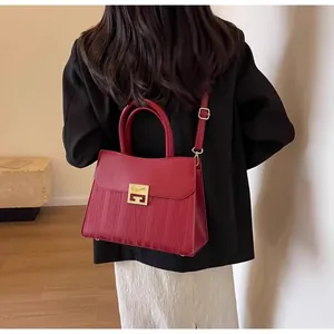 Detailed back view of a red leather bridal handbag with a golden clasp on a model