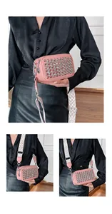 Pink crossbody camera bag featuring silver rivets and a wide geometric woven strap
