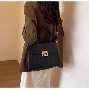 Detail of black trapezoid leather bag with gold G-logo hardware and slim shoulder strap