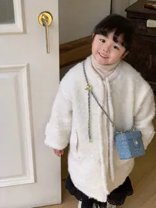 Détail d'un petit sac en denim matelassé avec chaîne et une veste blanche en polaire