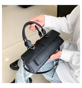 Detailansicht der schwarzen Ledertasche mit silbernen Beschlägen auf weißem Hemd