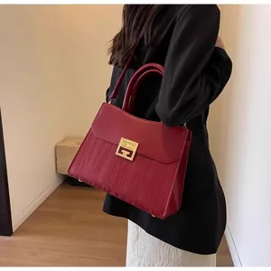 Detail of burgundy bridal handbag with gold metal clasp and wavy textured leather finish