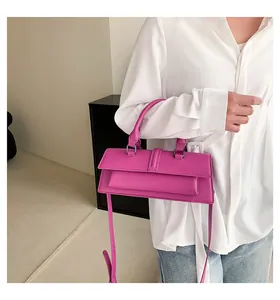 Detail einer pinkfarbenen rechteckigen Handtasche mit Glanzfinish und Silberbeschlag