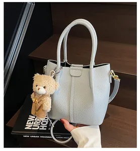 Detail of light blue textured leather bucket bag with a cute teddy bear plush charm
