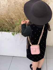 Mini sac boîte matelassé rose avec fermoir fleur dorée porté par un enfant dehors