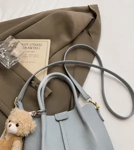 Detail of light blue pebble leather handbag with gold hardware and plush bear charm