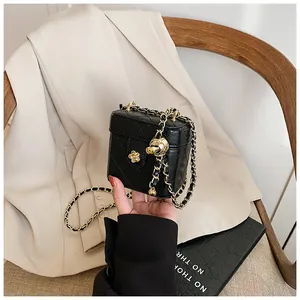 Détail du mini sac boîte noir matelassé avec chaîne dorée et fermoir fleur en métal