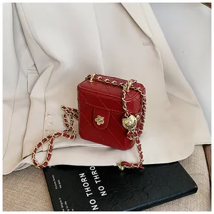 Détail du mini sac boîte rouge avec boule dorée et fermoir fleur de camélia