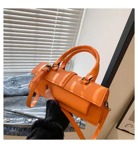 Details einer leuchtend orangefarbenen Baguette-Tasche mit Bronzeschnallen und Griff