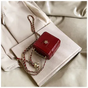 Détail du mini sac boîte rouge matelassé avec fermoir fleur dorée et bandoulière chaîne