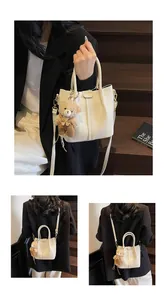 Detail of off-white lychee texture bucket bag with cute plush bear pendant accessory