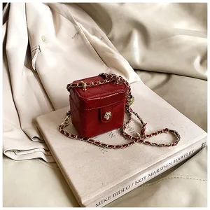 Détail du mini sac boîte rouge matelassé avec fermoir fleur doré et chaîne en cuir