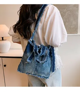 Detail view of denim tote bag with frayed edges and vintage washed finish on shoulder strap