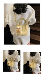 Detail of creamy yellow lychee grain leather bucket bag with a cute teddy bear charm