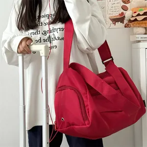 Macro detail of red nylon travel bag showing adjustable shoulder strap and side pocket