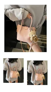 Detailed view of pink leather bucket bag with cute bear charm and adjustable strap