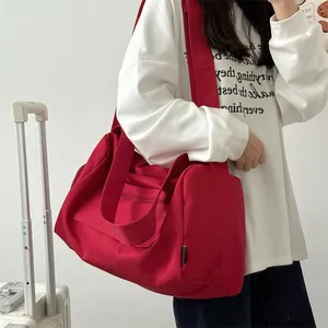Detail of red travel bag with adjustable strap and front zipper pocket for gym use