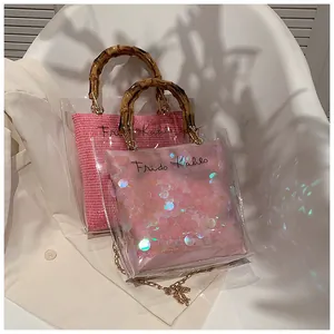 Detail of transparent PVC handbag featuring bamboo handles and pink sequin inner pouch