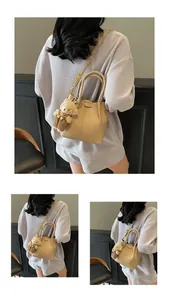 Detailed view of beige textured leather bucket bag with a cute teddy bear charm
