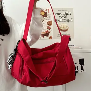Detailed view of red large-capacity travel bag with checkered strap and charm on model