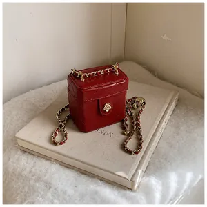 Détail d'un mini sac boîte en cuir matelassé rouge avec fermoir fleur de camélia doré