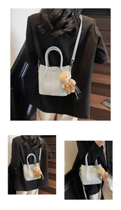 Macro shot of light blue pebbled leather tote bag with cute bear charm and golden hardware