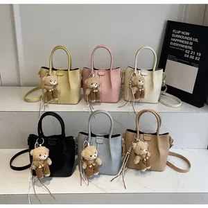 Six colors of pleated leather bucket bags with teddy bear charms on marble steps