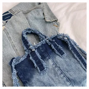 Detailed close-up of blue denim tote bag with frayed edges and distressed tassels