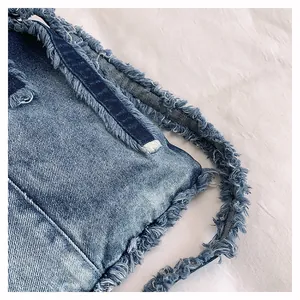 Detailed macro view of washed denim tote bag showing heavy fringe and frayed edges