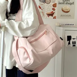 Detailed view of pink nylon travel bag featuring multiple zipper pockets and wide shoulder strap