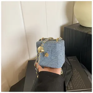 Détail du sac boîte en denim bleu avec chaîne dorée et fleur de camélia décorative