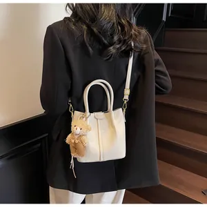 White lychee grain bucket bag with adjustable gold buckle strap and cute bear charm