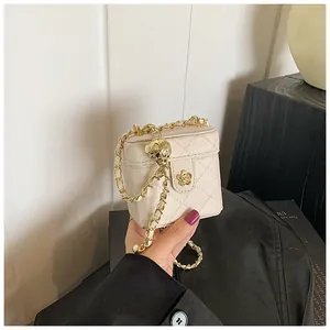 Détail du mini sac boîte matelassé crème avec fermoir camélia et chaîne réglable dorée