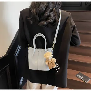 Detail of light blue bucket bag with leather texture and cute bear charm on a model