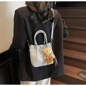 Detailed shot of light blue lychee pattern leather bucket bag with a cute teddy bear charm