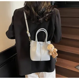 Close-up of light blue leather bucket bag with cute bear charm on a staircase