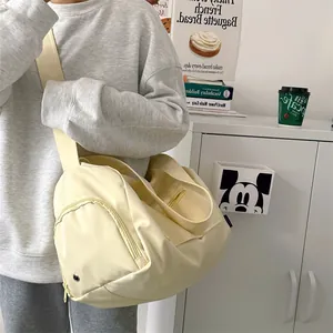 Detail of a beige cylinder sports bag with nylon material and wide shoulder strap